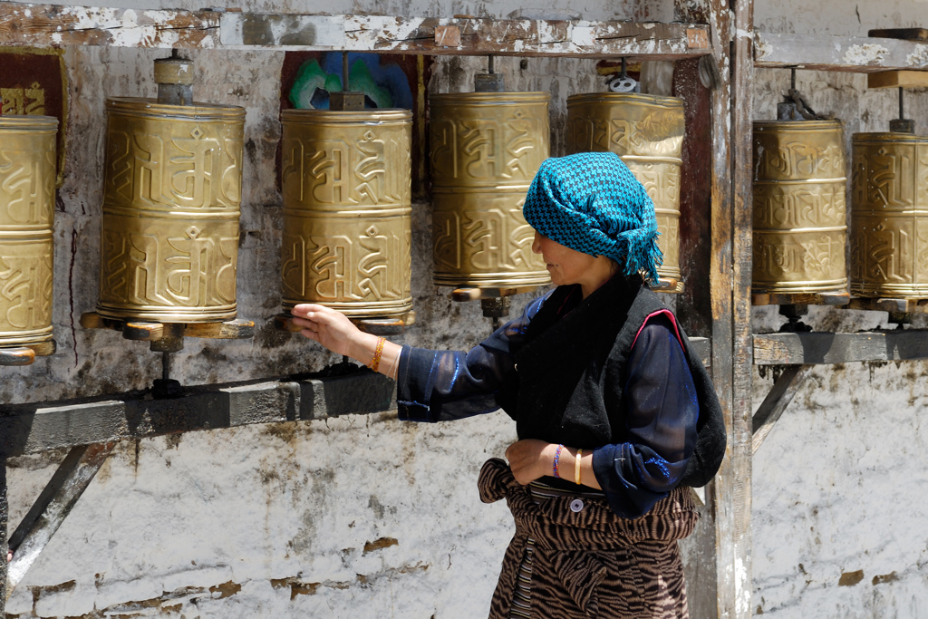 Vrouw draait gebedsmolens bij een klooster tijdens groepsrondreis Tibet en Nepal.