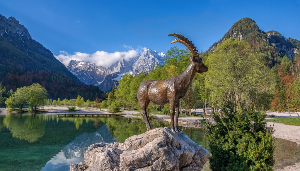 Standbeeld van een steenbok aan een bergmeer met de Alpen op de achtergrond tijdens groepsrondreis Centraal Europa.