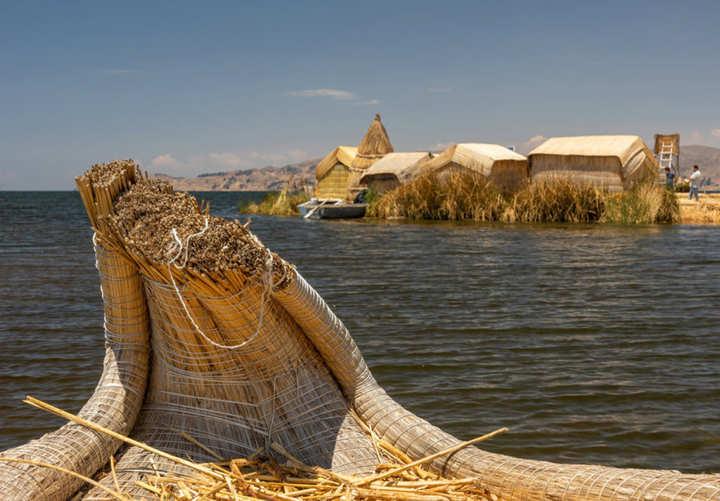 Rieten boot en drijvende rieteilanden op het Titicacameer in Peru.