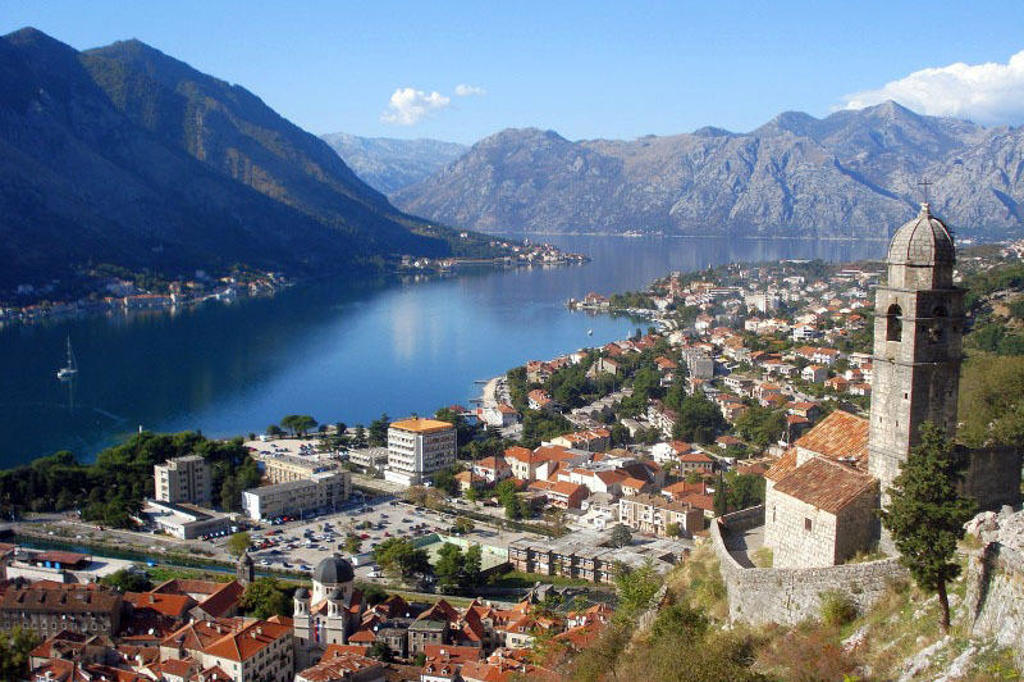 Uitzicht over de Baai van Kotor en de oude stad Kotor, Montenegro, met kerktoren en bergen op de achtergrond.