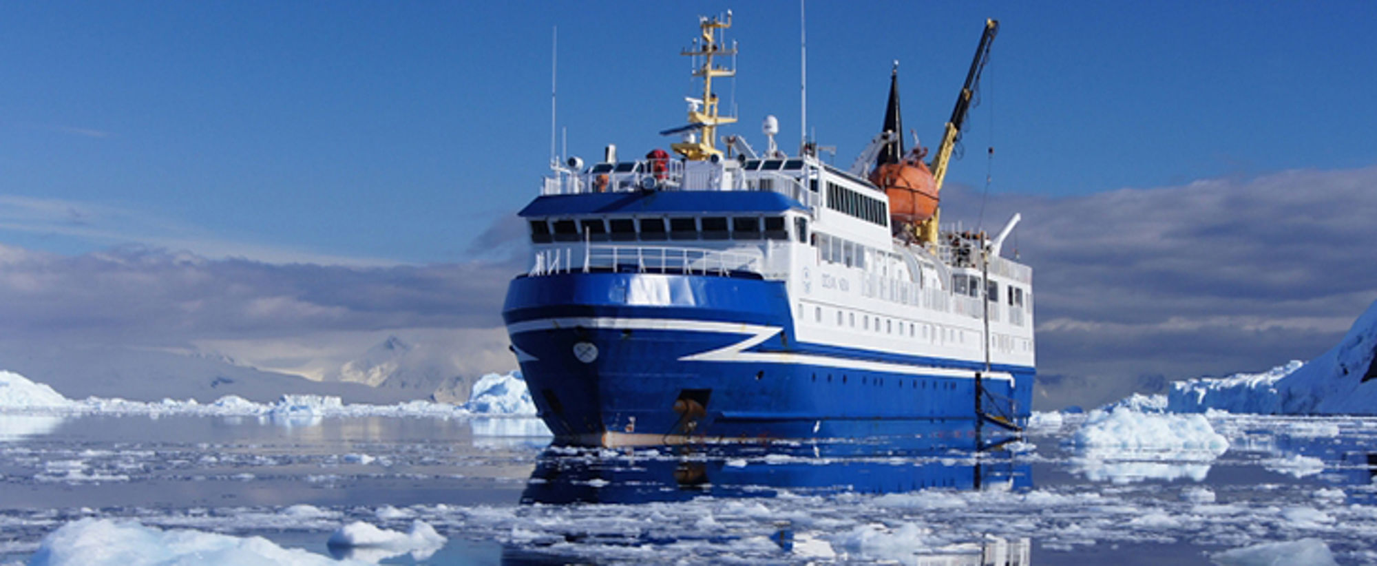Schip richting Groenland en Spitsbergen Blauw-wit expeditieschip vaart door drijvend pakijs tussen ijsbergen.