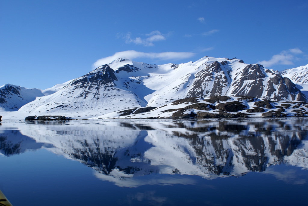 Besneeuwde bergen op Spitsbergen weerspiegeld in kalm water tijdens een cruise met zeilschip Noorderlicht.