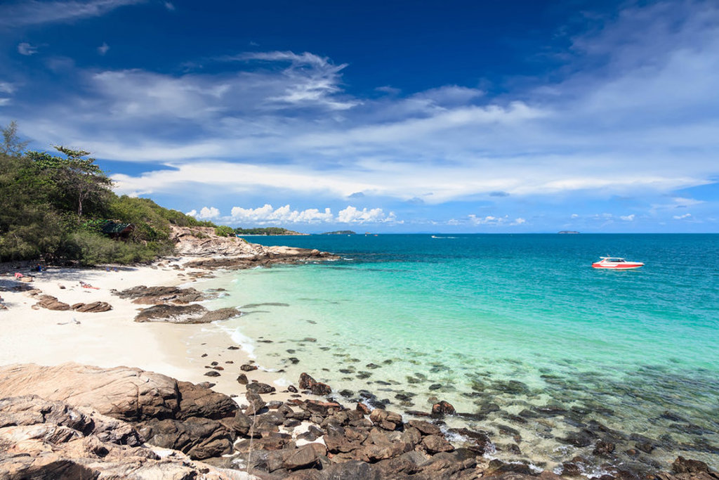 Rotsachtig strand met wit zand en helderblauwe zee in Thailand, een hoogtepunt van de groepsrondreis.