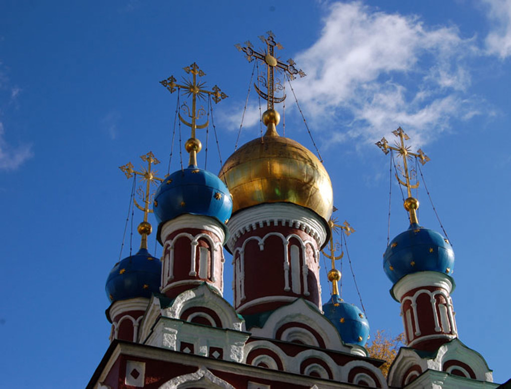 Gouden en blauwe uivormige koepels van een Russisch-orthodoxe kerk tegen een blauwe lucht.