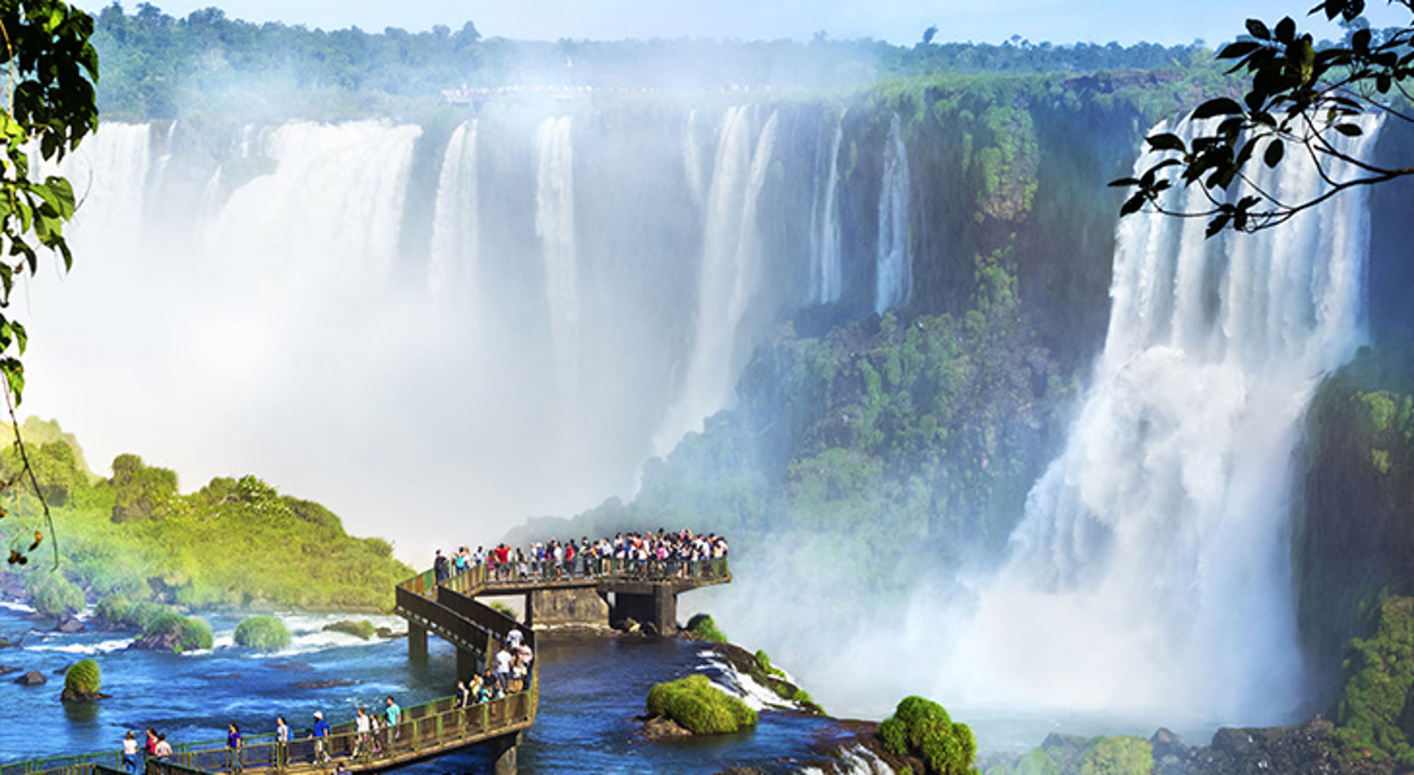 Iguazu watervallen Uitzicht op de Iguazú-watervallen met bezoekers op een uitkijkplatform boven de rivier.