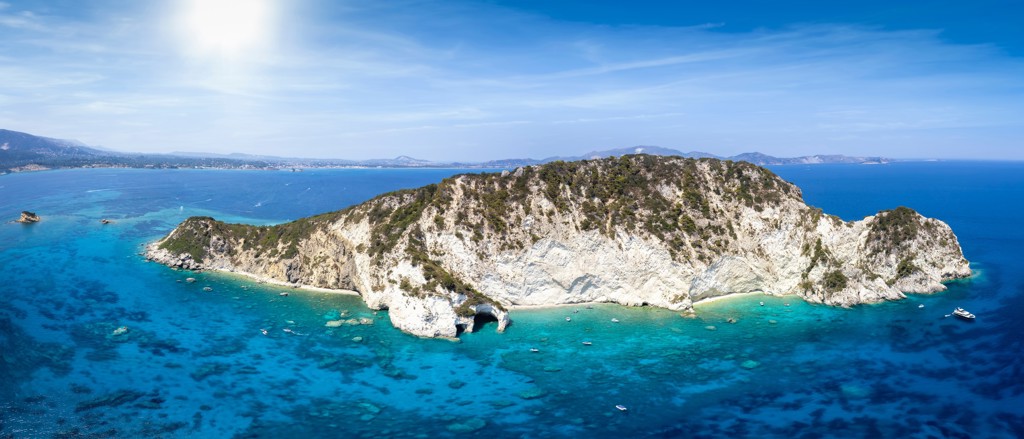 Rotsachtig Grieks eiland met witte kliffen en turquoise zee, gezien vanaf zee tijdens een 22-35ers reis Griekenland.