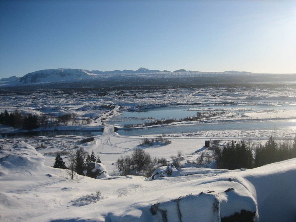 Sneeuwlandschap met bevroren rivier en bergen tijdens groepsrondreis IJsland in de winter.