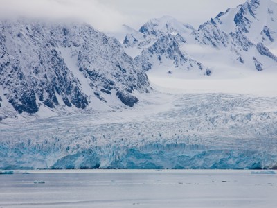 Gletsjerfront met ijsbergen en besneeuwde bergen in Spitsbergen.