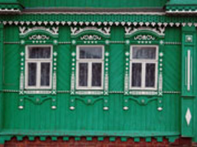Groene houten gevel met sierlijke witte kozijnen en houtsnijwerk in Rusland.