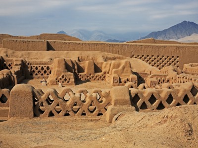 Leemarchitectuur en muren van Chan Chan bij Trujillo, Noord-Peru, met bergen op de achtergrond.