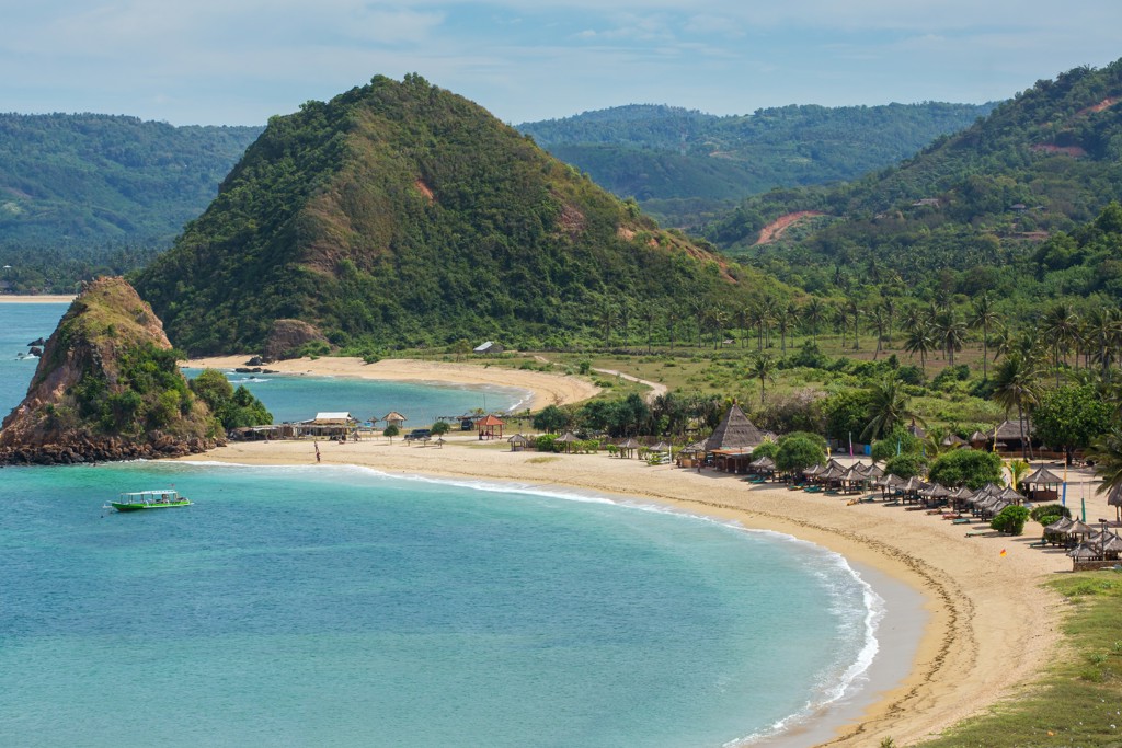Tropisch strand met turquoise zee en groene heuvels op Lombok, Indonesië.