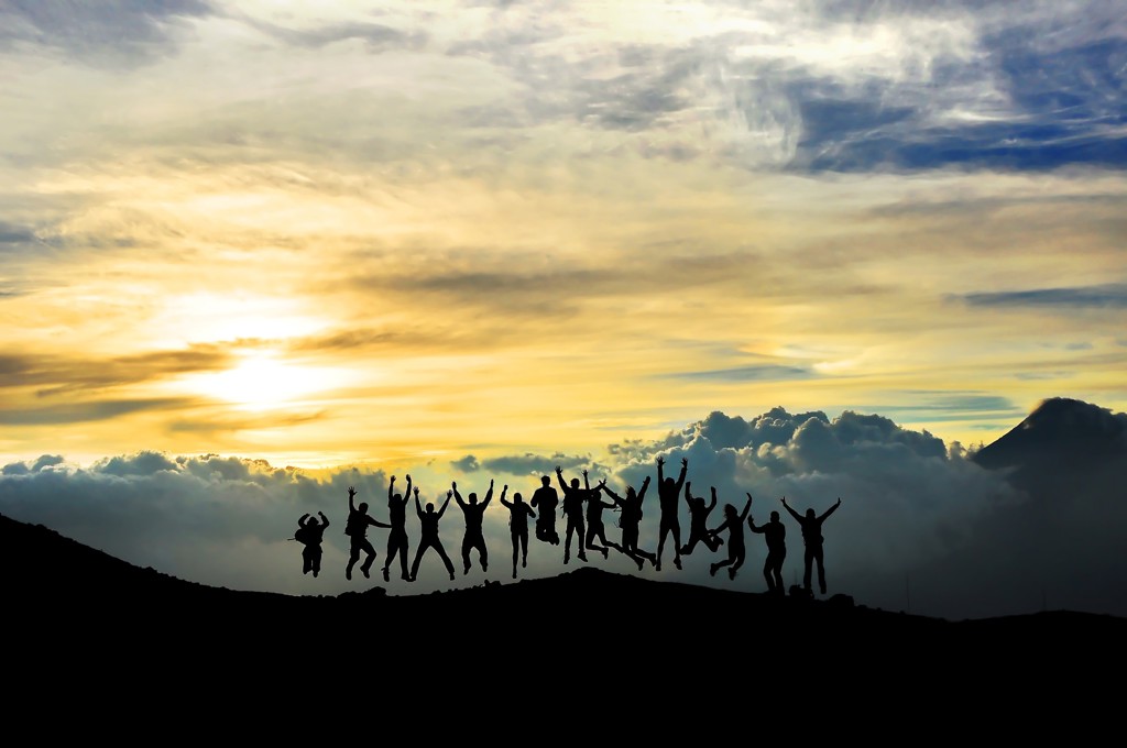 Silhouetten van reizigers die springen bij zonsopgang op een berg in Guatemala tijdens een familiereis.
