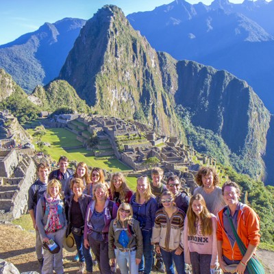 Groep reizigers bij Machu Picchu met uitzicht op de Inca-ruïnes en de bergen van Peru.