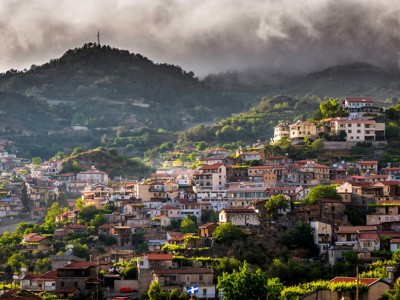 Heuveldorp in het Troodosgebergte op Cyprus, met rode daken en mist boven de groene bergen.