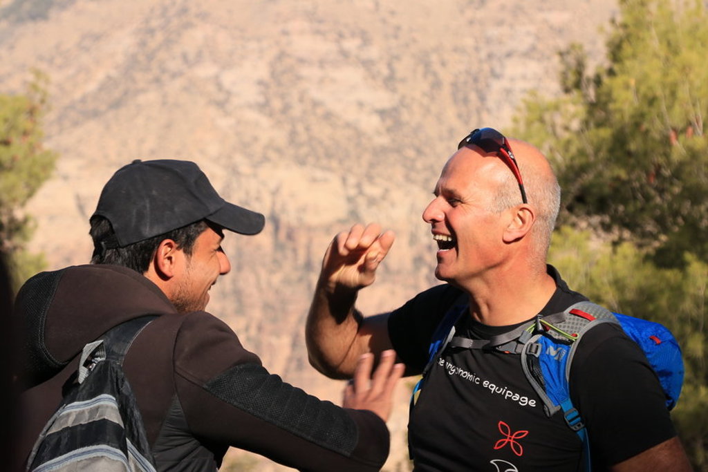 Twee wandelaars lachen en geven elkaar een high five tijdens een groepsrondreis door Jordanië.