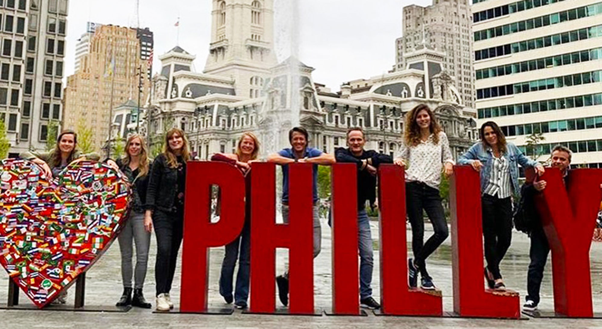 Groep reizigers poseert bij het I LOVE PHILLY-bord bij Philadelphia City Hall.