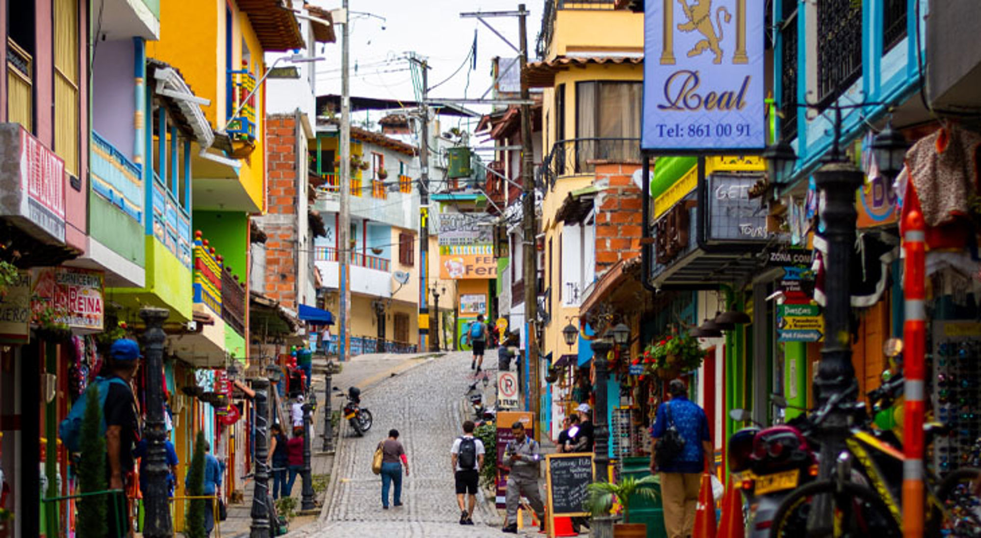 Kleurrijke straat met winkels en wandelaars in een Colombiaanse stad.