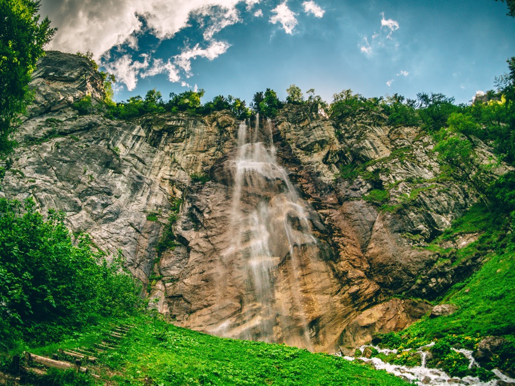 Hoge waterval langs steile rotswand in groen berglandschap in Bosnië en Herzegovina.