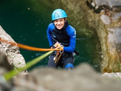 Kind abseilt met helm en wetsuit in een kloof bij de Río Cinca in Aragón, Spanje.