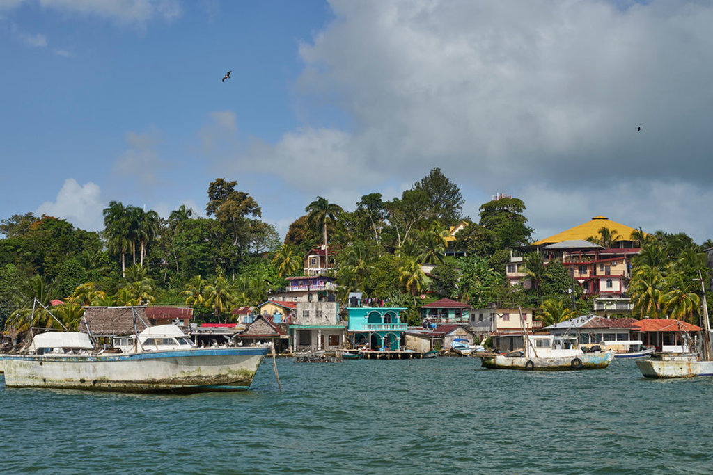 Kustdorp aan het water in Guatemala met kleurrijke huizen tussen palmen en boten in de baai.