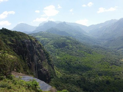 Uitzicht over een groene bergvallei met steile rotswand tijdens de Route Sri Lanka.