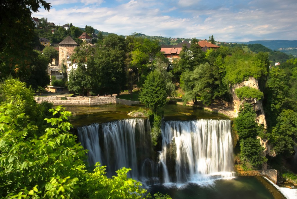 Waterval bij Jajce met historische gebouwen en groen landschap, tijdens groepsrondreis Zuid-Oost Europa.