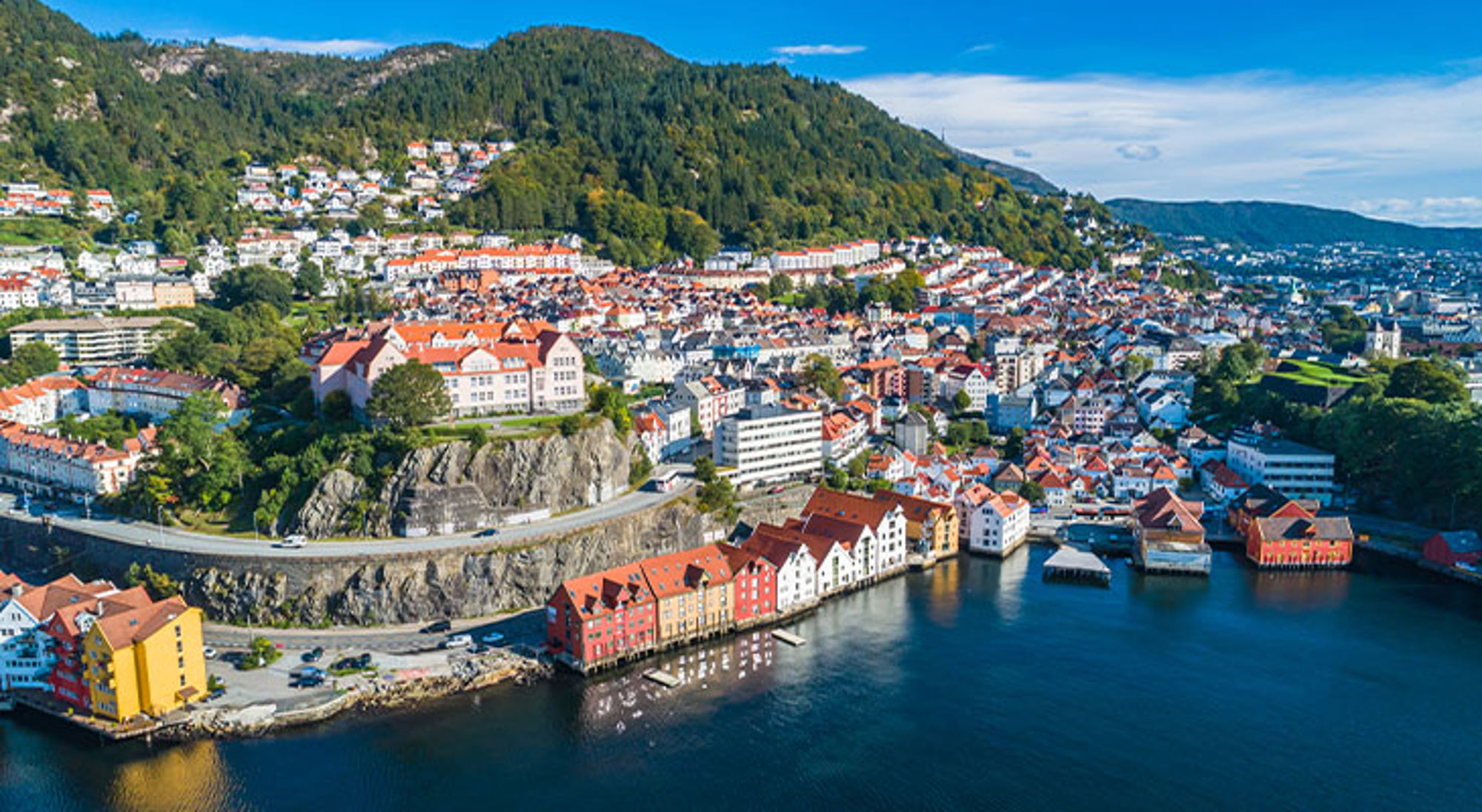 Bergen in Noorwegen Panoramisch uitzicht op Bergen met kleurrijke houten huizen aan de haven en groene heuvels op de achtergrond.