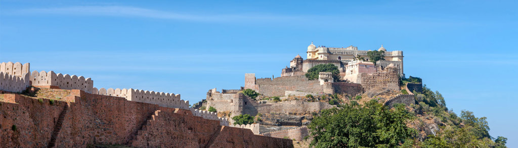Fort en paleis op een heuvel in Rajasthan, India, met stadsmuren onder een blauwe lucht.