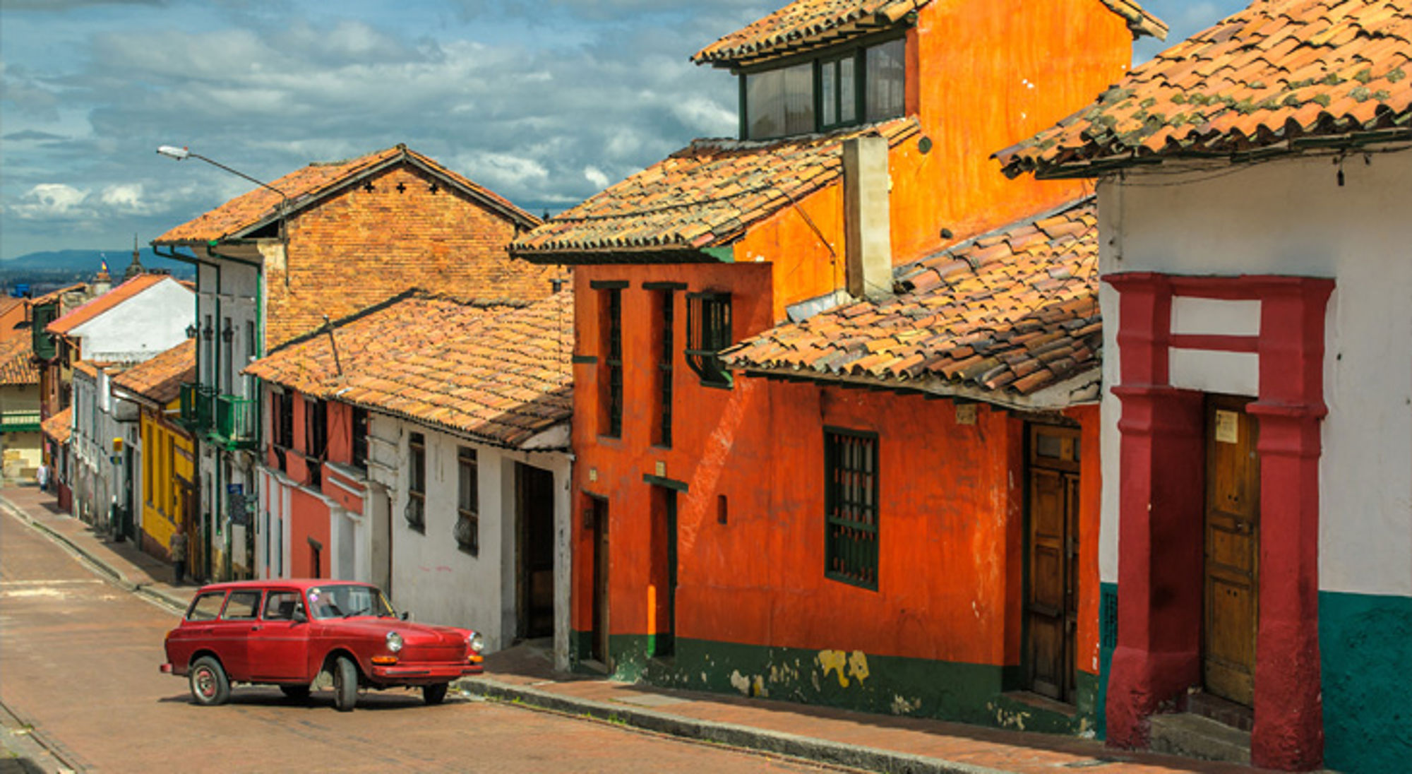 La Candelaria Gekleurde straat met traditionele huizen en rode auto in Colombia.