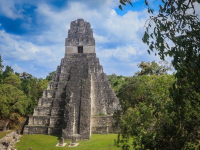 Maya-tempel in Tikal, Guatemala, omringd door jungle onder een blauwe lucht.