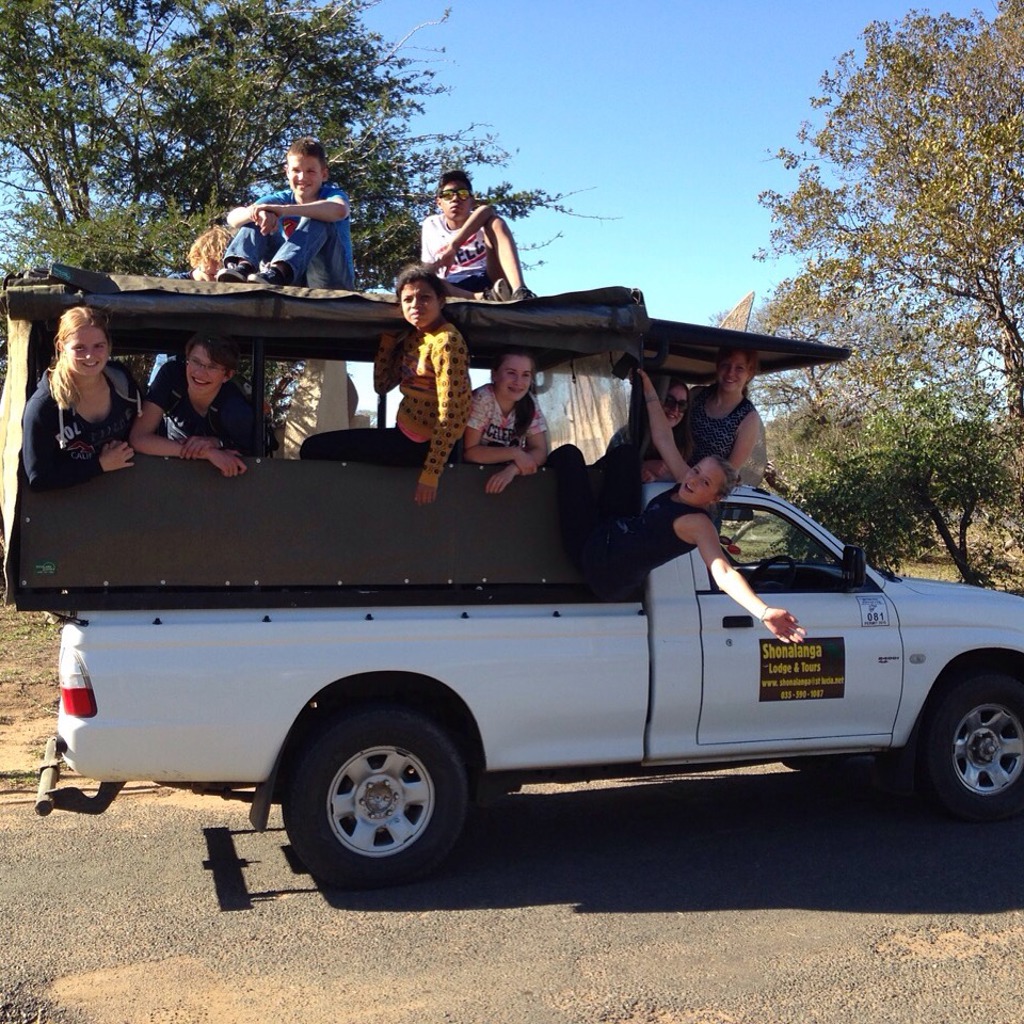 Gezin op safari in open jeep tijdens familiereis Zuid-Afrika en eSwatini, met kinderen die uit de wagen hangen.
