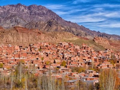 Rode lemen huizen van het dorp Abyaneh tegen de bergen in Iran tijdens Route Iran, 14 dagen.