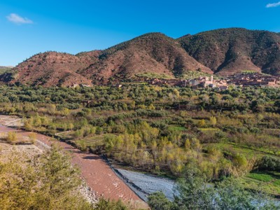 Groene vallei met rivier en dorp aan de voet van het Atlasgebergte in Marokko.
