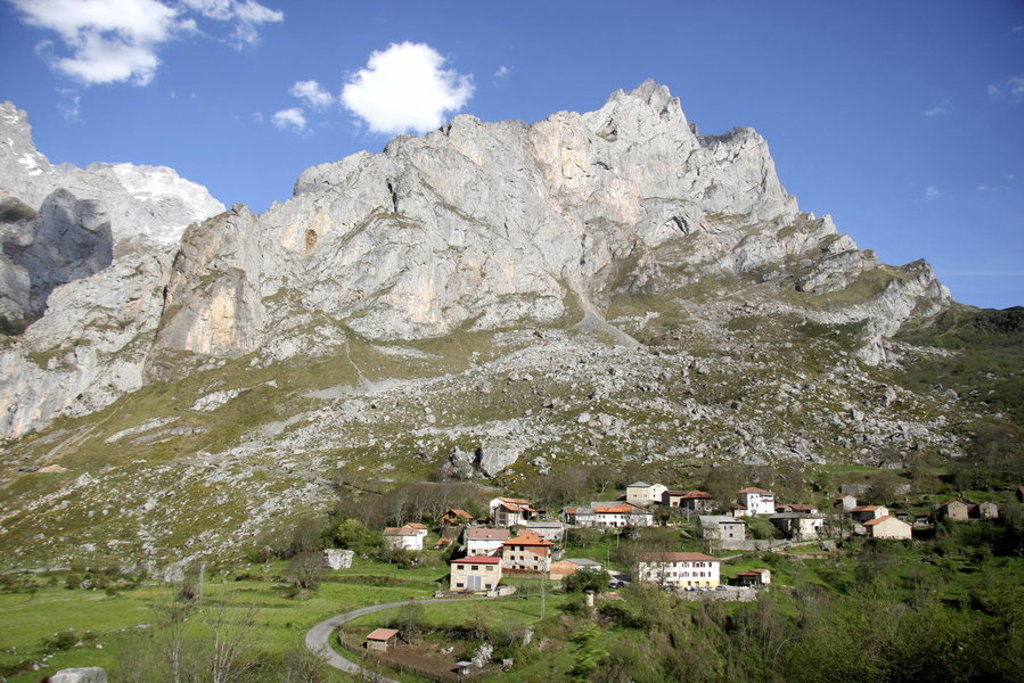 Berglandschap met dorpje in de Picos de Europa, Spanje, onder een blauwe lucht.