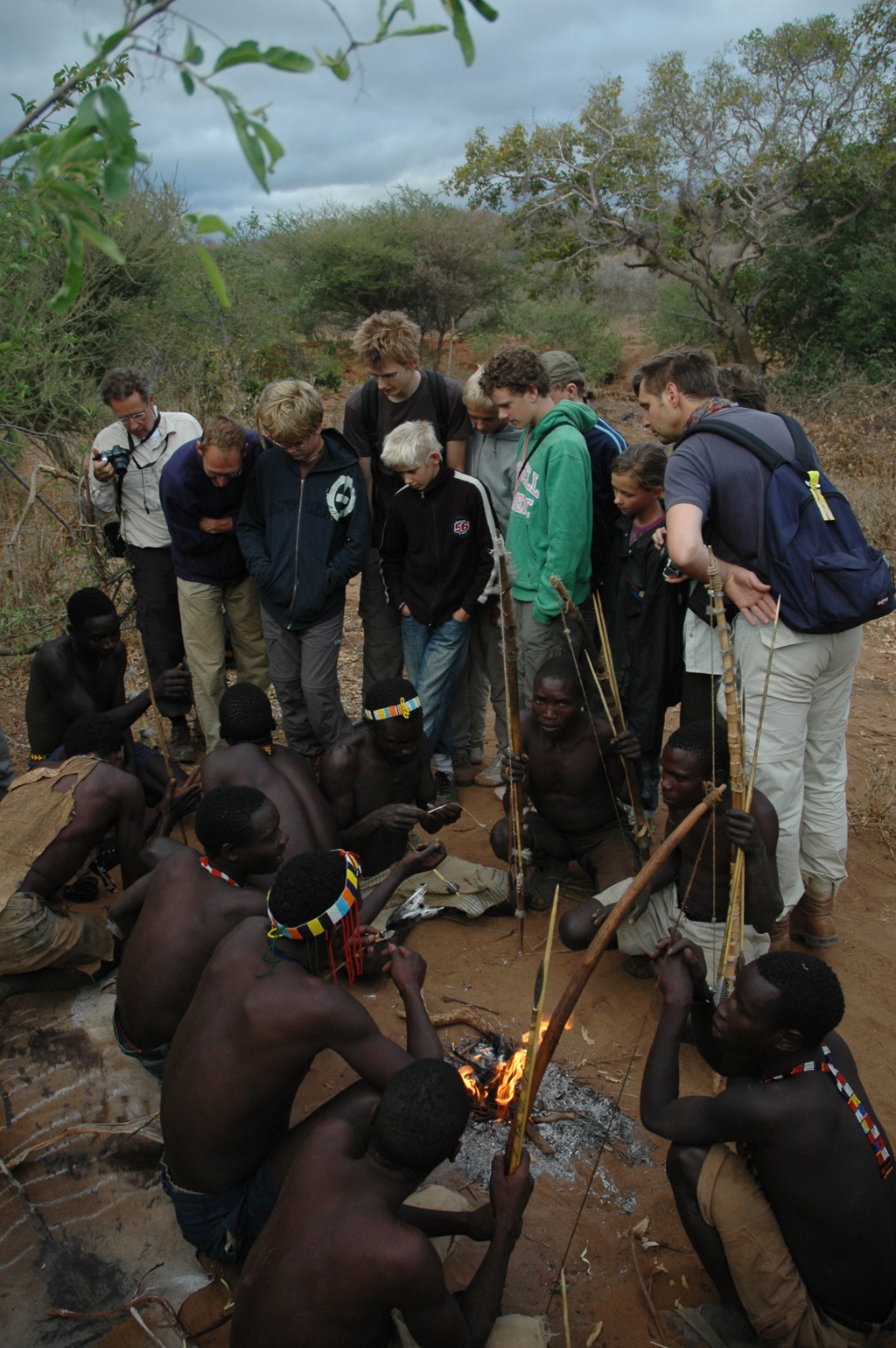 Familiereis in Kenia: reizigers kijken toe bij een demonstratie boogschieten rond een kampvuur.