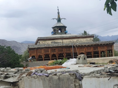 Traditionele moskee met houten gevel en minaret in Baltistan, Pakistan, met bergen op de achtergrond.
