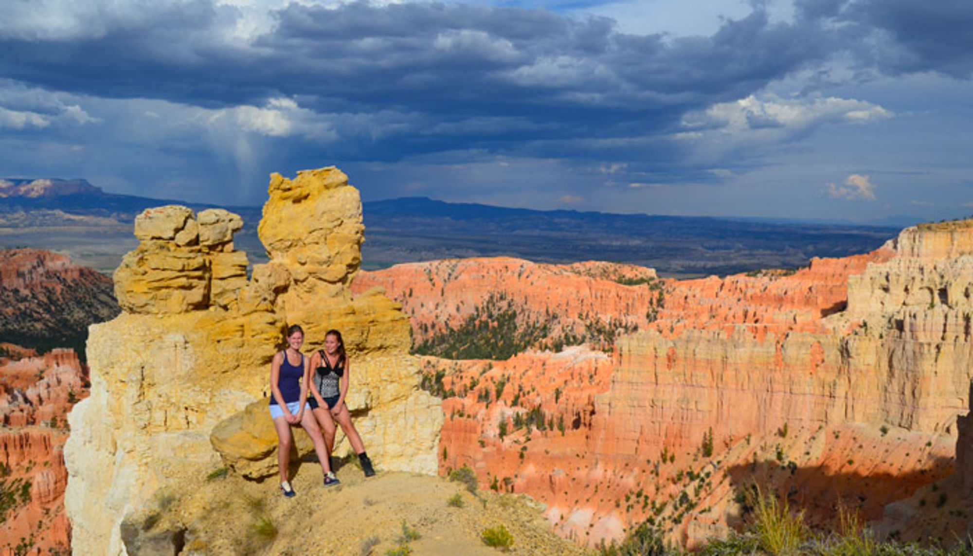 Twee wandelaars poseren bij rotsformatie met uitzicht op de rode canyons van Bryce Canyon National Park.