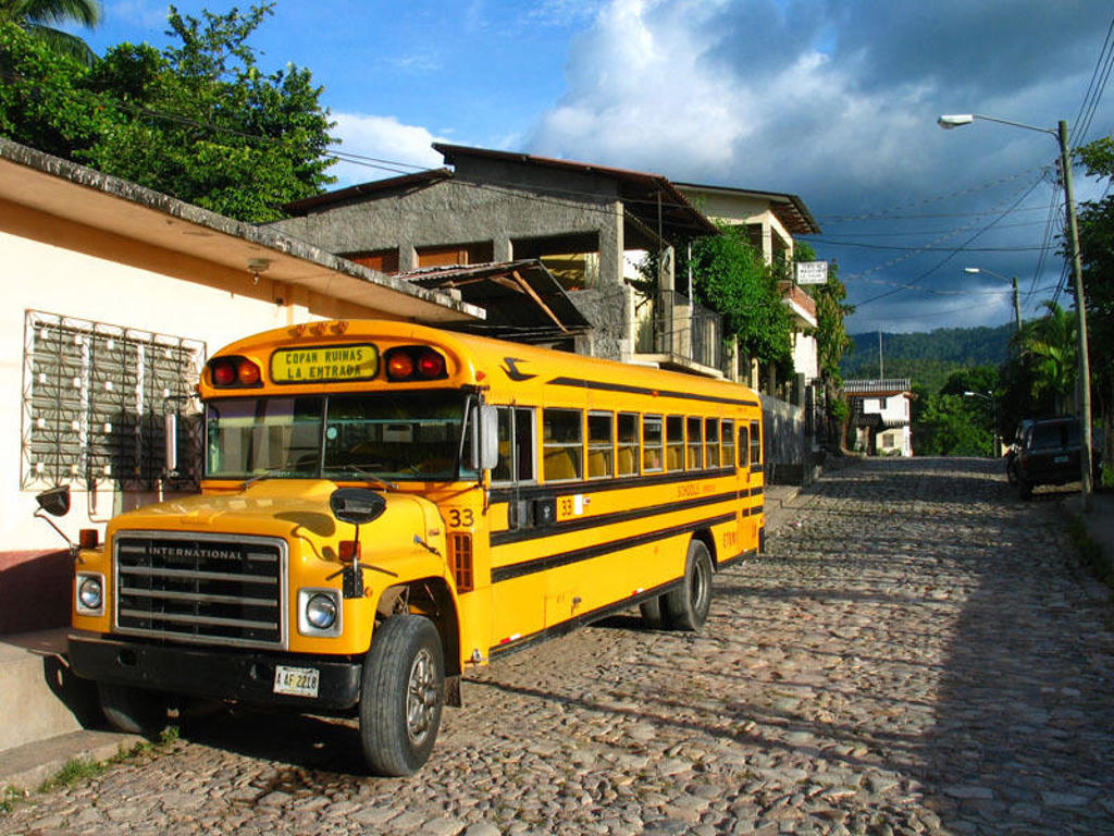 Gele schoolbus op een geplaveide straat in Guatemala tijdens groepsrondreis Mexico, Guatemala en Honduras.
