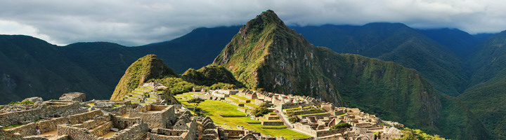 Machu Picchu in Peru, met Inca-ruïnes en groene bergtoppen onder een bewolkte lucht.