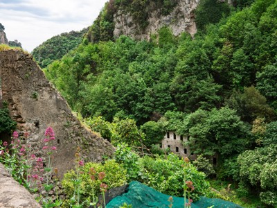 Groene kloof met rotswanden en ruïnes langs de wandelroute op de Amalfikust, Italië.