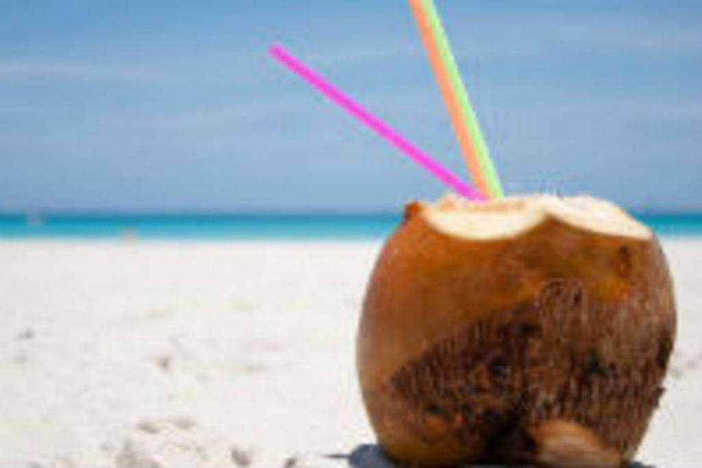 Kokosnoot met rietjes op een wit zandstrand aan zee in Cuba.