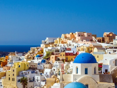 Witte huizen en blauwe koepelkerk in Oia op Santorini, met uitzicht op de Egeïsche Zee.