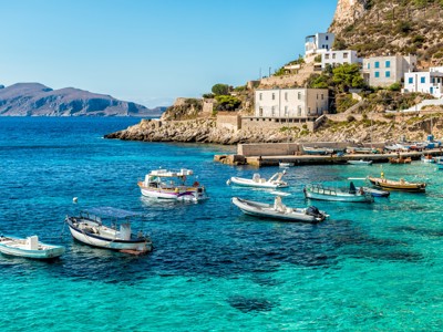 Kleurrijke vissersbootjes in een turquoise baai bij een kustdorp in West-Sicilië.