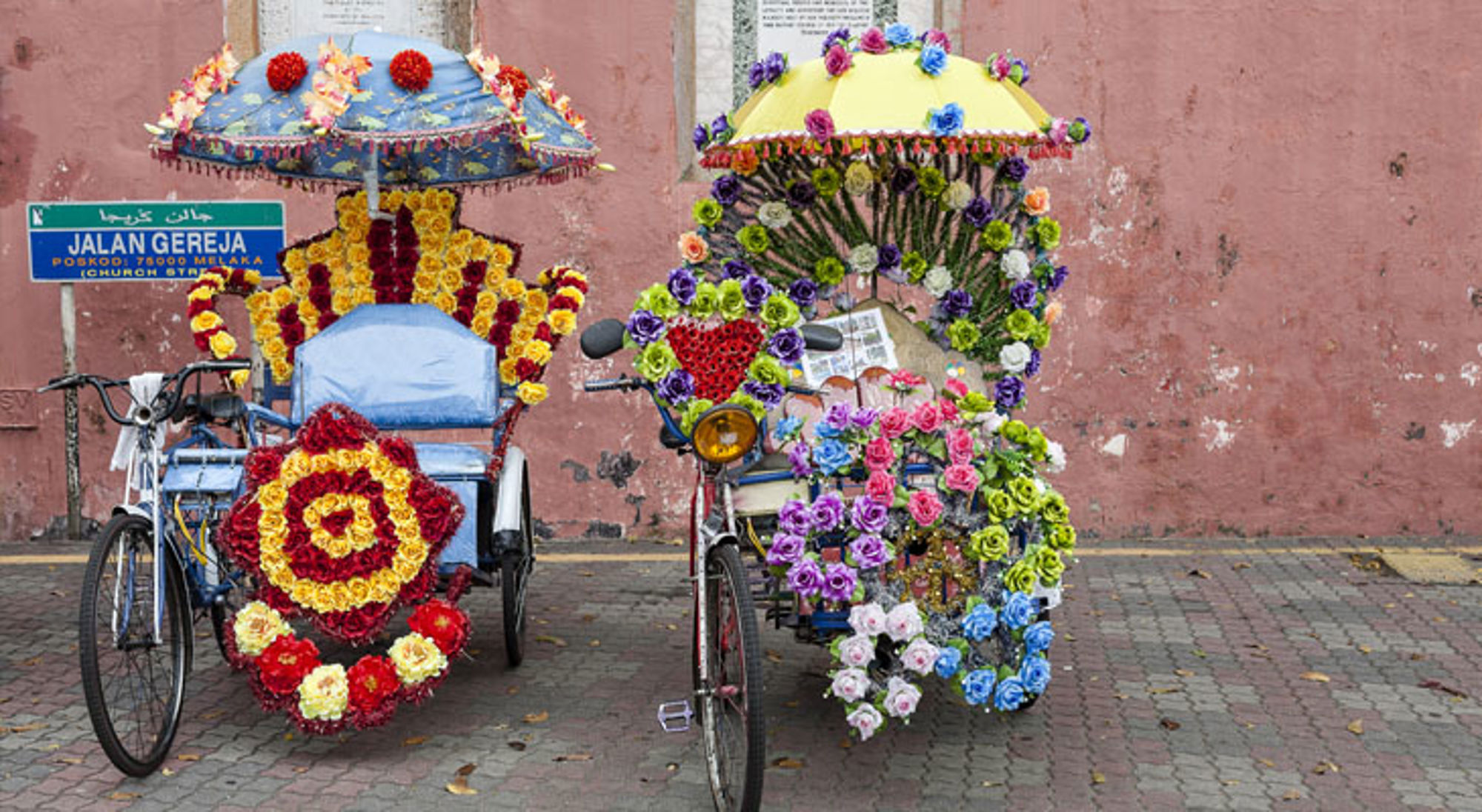 Malakka Maleisië Twee kleurrijk versierde fietstaxi’s met bloemenparasols op straat in Melaka, bij Jalan Gereja.