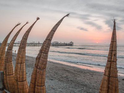 Rieten vissersboten op het strand van Huanchaco bij zonsondergang, langs de Route Noord-Peru.