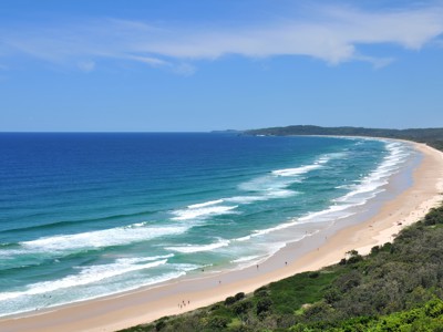 Uitzicht op een lang zandstrand met golven aan de kust van Australië.