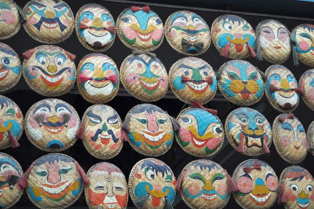 Gekleurde Vietnamese hoeden met handgeschilderde gezichten op een markt tijdens een groepsrondreis Vietnam.