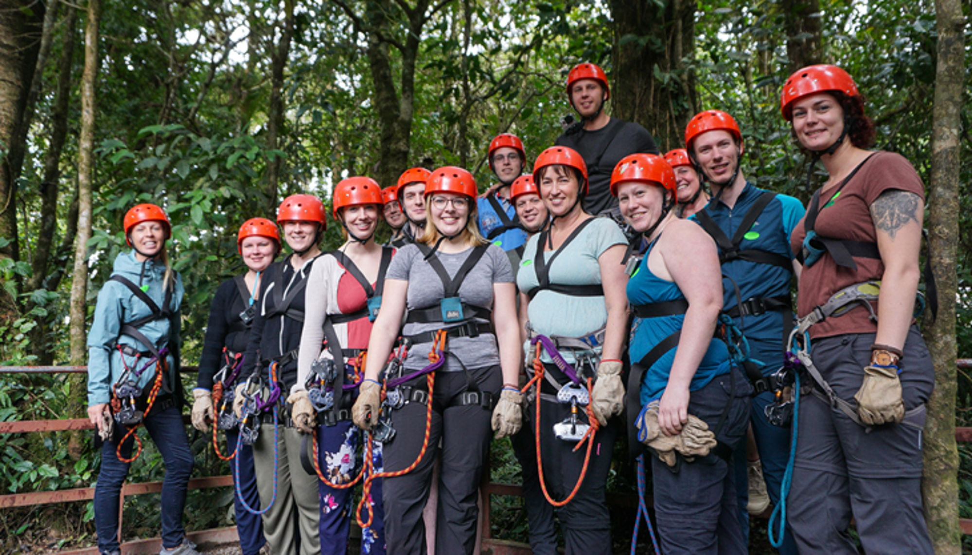 Groep deelnemers met helmen en klimgordels klaar voor canopy tour in het regenwoud.