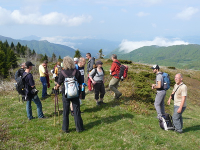 Wandelgroep met rugzakken op een bergplateau met uitzicht op groene bergen tijdens de route Bosnië, 8 dagen.