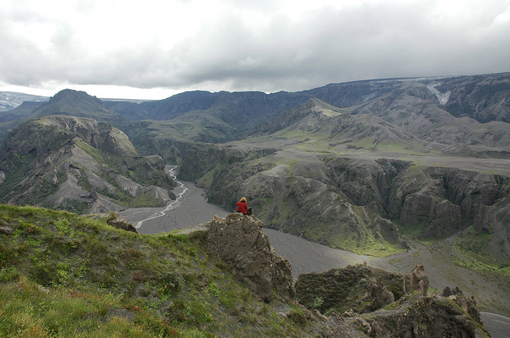 Wandelaar kijkt uit over de canyon en rivier in het berglandschap van IJsland tijdens een groepsrondreis kamperen.